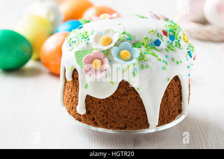 Easter cake with glace icing decoration and coloured easter eggs on a holiday table Stock Photo