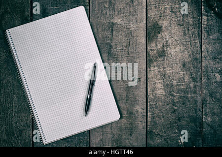 Open notebook into the cell, clean sheets lying on a wooden surface, empty space on the right Stock Photo