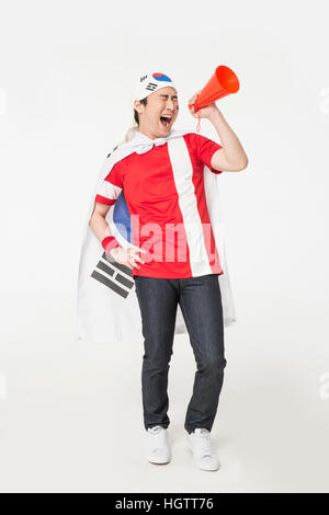 Young smiling Korean cheerleader man shouting through a megaphone Stock Photo