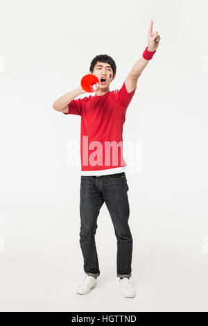 Young Korean cheerleader man shouting through a megaphone Stock Photo