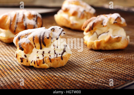 Cream puff cake with filling and chocolate icing. Catering set. Stock Photo