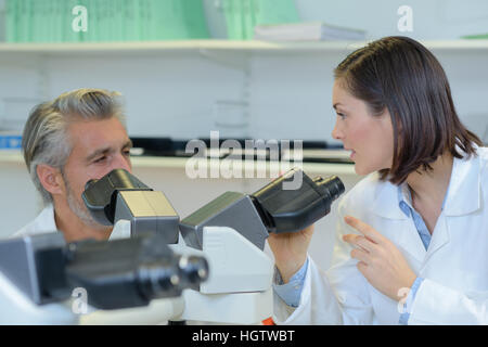 scientists examining samples under microscope Stock Photo
