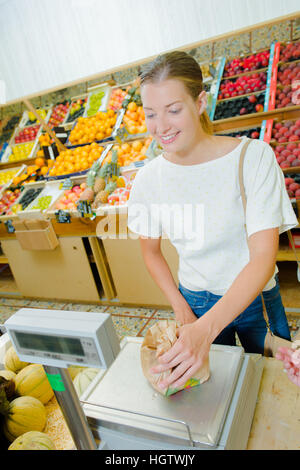 Lady weighing produce in a paper bag Stock Photo