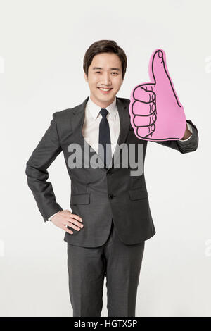 Young smiling business man posing with thumb-up sign Stock Photo