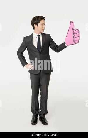 Side view of young businessman cheering with thumb-up sign Stock Photo