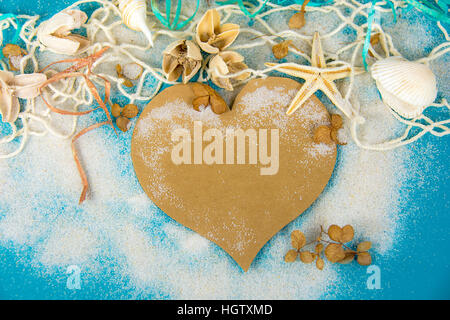 brown heart and seashells in net and sand on turquoise painted wood Stock Photo
