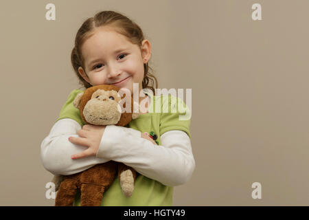 a beautiful young girl holding her favorite stuffed monkey Stock Photo