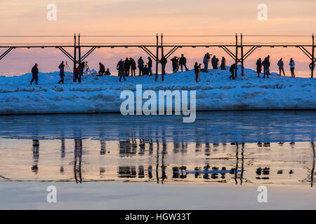 People along the South Pier at Grand Haven Lighthouse at sunset, where the Grand River enters Lake Michigan, Michigan, USA Stock Photo