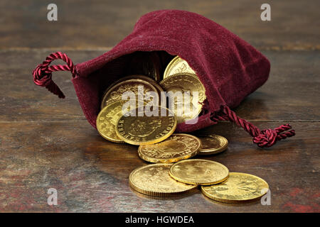 various European circulation gold coins from the 19th/20th century in a velvet purse on rustic wooden background Stock Photo