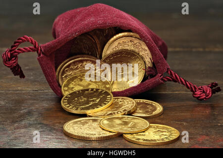 various European circulation gold coins from the 19th/20th century in a velvet purse on rustic wooden background Stock Photo
