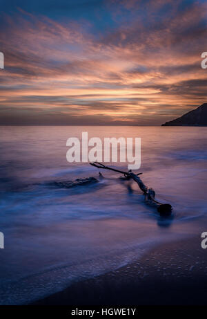 Driftwood and amazing sunset on South Corfu beach. Stock Photo