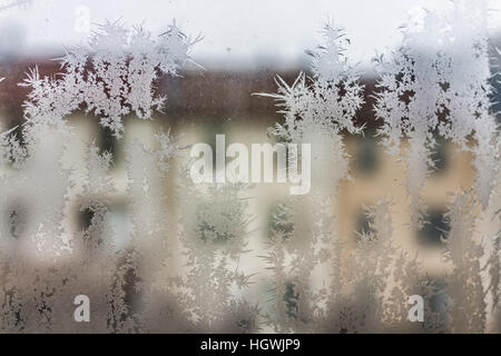 Ice crystals on window with view of town houses during winter Stock Photo
