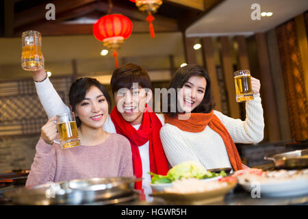 Young friends drinking beer in hotpot restaurant Stock Photo