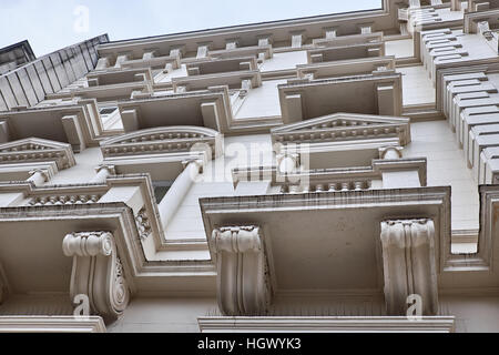 Sections of a plastered facade with elaborate decorations around the windows and balconies of a building in London City Stock Photo