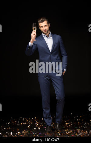 Young man celebrating holding glass of champagne on black Stock Photo