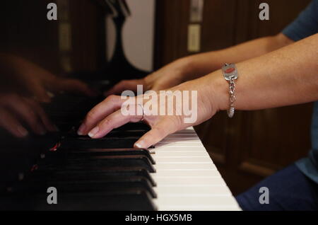 Woman's hands playing chord on black and white grand piano Stock Photo