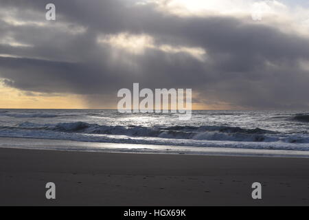 Sun peaks through the storm clouds and illuminates the waves Stock Photo