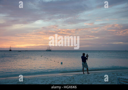 Aruba, Caribbean - September 25, 2012: Photographer at the Sunset with anchored sail boats on sea by the bay. The image was taken in Aruba, in the Car Stock Photo