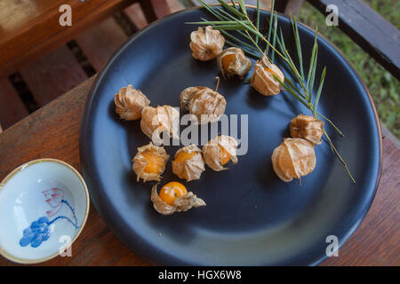 Cape gooseberry (Physalis) on black plate and small Chinese tea cup