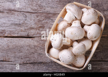 Fresh champignons in a container on an old wooden table. top view Stock Photo