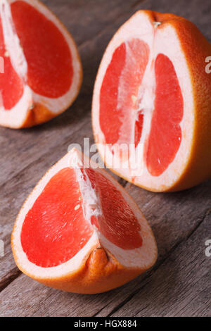 large pieces of red grapefruit on the old wooden table closeup. vertical Stock Photo