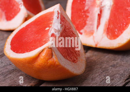large pieces of red grapefruit on the old wooden table closeup. horizontal Stock Photo
