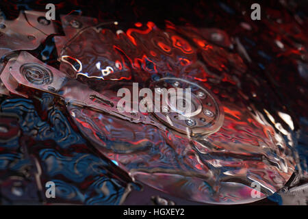 Opened Computer hard disk drive in studio with dark red and blue reflection, conceptual creative association Stock Photo