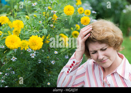 Woman suffering from headache allergic to flowers Stock Photo