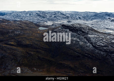 A dusting of snow covers barren and inhospitable mountain peaks on a highland tundra plateau. Stock Photo