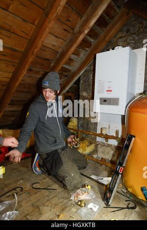 Plumbers fitting new boiler  in a loft in an old house in Aberdeen Scotland Stock Photo