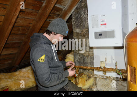 Plumbers fitting new boiler  in a loft in an old house in Aberdeen Scotland Stock Photo