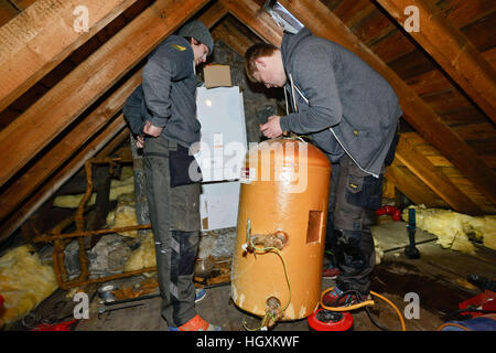 Plumbers fitting new boiler  in a loft in an old house in Aberdeen Scotland Stock Photo