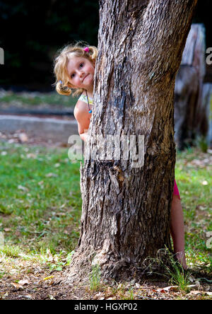 Little girl plays hide and seek Stock Photo