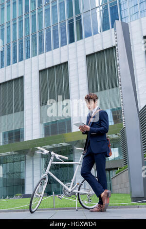 Businessman using tablet standing at bicycle Stock Photo