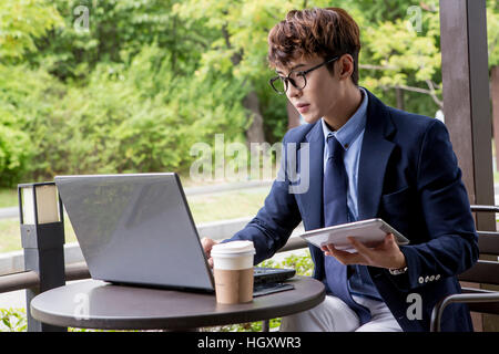 Businessman using tablet and notebook computer at cafe Stock Photo