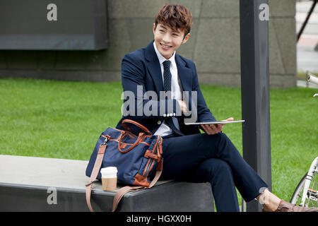 Smiling businessman sitting on bench Stock Photo
