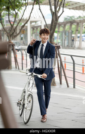 Smiling businessman walking with bicycle Stock Photo