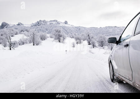 Car driving on snowy  winter mountain road Stock Photo