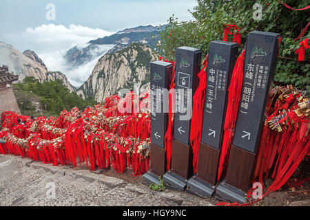 Direction signs in majestic Huashan mountains with memorable red ribbons and traditional padlocks of lovers people in Huashan mo Stock Photo