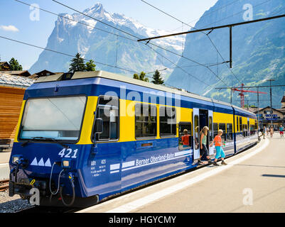 Children leave a train at Grindelwald Switzerland with the Wetterhorn peak behind Stock Photo