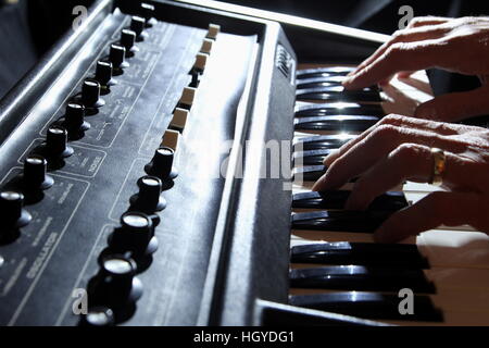 Backlit shallow focus shot of man's hands playing an old 1970s synth keyboard Stock Photo