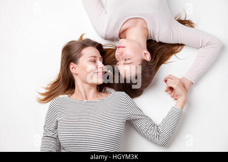 Portrait of young and happy sisters lying on the floor Stock Photo