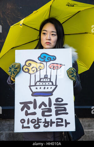 London, UK. 14th January, 2017. A member of the UK's Korean community holds a silent protest in Trafalgar Square to mark 1,000 days since the Sewol ferry disaster, to remember the victims and to demand that the Korean government not only raises the ferry without dismantling it to enable a thorough inquiry and recovery of all missing victims but also punishes those responsible and enacts anti-disaster regulations in London, UK. Credit: Mark Kerrison/Alamy Live News Stock Photo