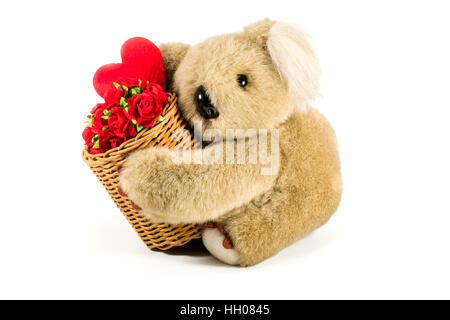 Cute teddy bear carrying bamboo basket full of red roses and heart on white background Stock Photo