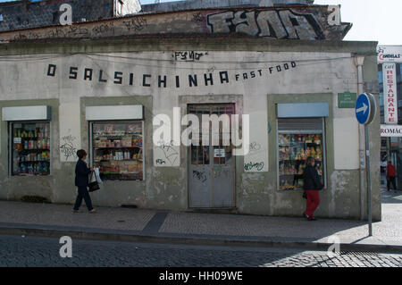 Portugal, Europe: details of the streets and alleys of Porto with people walking in front of a grocery shop in the Old City Stock Photo