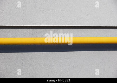 Yellow gas pipe in front of residential building wall Stock Photo