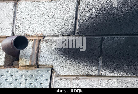 Metal exhaust pipe coming from a block built building with soot stains ...