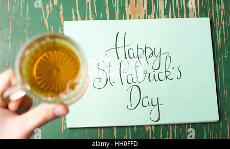 Happy St Patrick day calligraphy card and beer in hand Stock Photo
