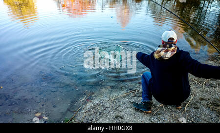 Fisherman with fishing rod and landing net during pulling out Stock Photo