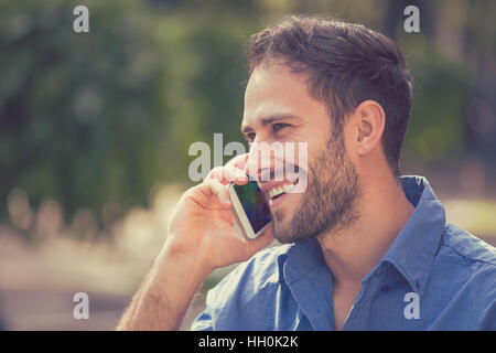 portrait handsome young happy smiling urban professional man using talking on smart phone. Businessman holding mobile smartphone Stock Photo